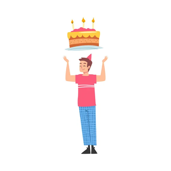 Ragazzo gioioso nel cappello del partito con la torta festiva sopra la sua testa, persona felice con il simbolo di festa, illustrazione vettoriale di stile del fumetto di concetto di compleanno felice — Vettoriale Stock