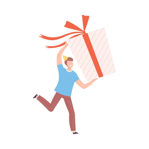 Mladý muž drží obrovský dárek box s červeným lukem, Drobná osoba slaví narozeniny nebo důležitou událost karikatura styl vektorové ilustrace — Stockový vektor