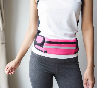 Beyaz bluz giyen, spor olsun diye pembe bel çantalı bir kadın..