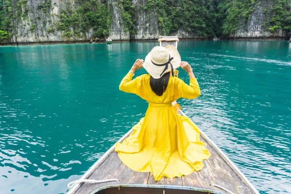 Sarı elbiseli bir kadın, yerel uzun kuyruklu bir tekneye biniyor, Phi Phi Adası 'na gidiyor, Krabi, Tayland.