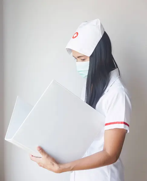 The female nurse wears mask protect from coronavirus and read document file.