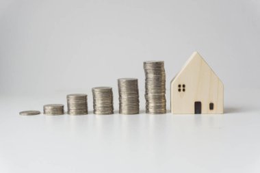 Yükseklik, beyaz arkaplan, iş fikri, iş büyümesi sırasına göre dizilmiş gümüş sikkeleri olan beyaz ahşap evler.