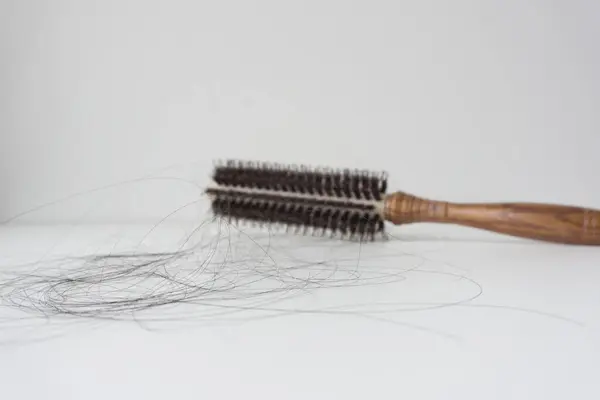 Hair brush with hair loss on white background.