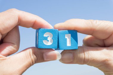 Mavi gökyüzü arka planında otuz bir numara tutan kadınların eli..