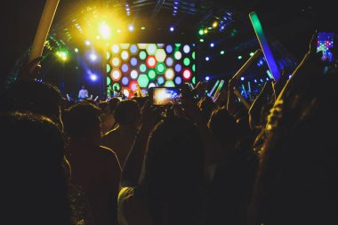 Konserdeki kalabalık siluetleri, elleri havada insanlar..