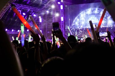 Konserdeki kalabalık siluetleri, elleri havada insanlar..