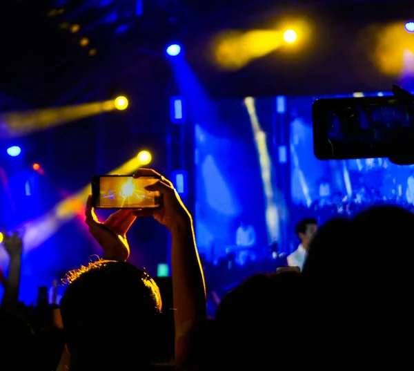 Bulanık insanlar akıllı telefonlar ve eğlenceli konserlerle fotoğraf çekiyorlar..