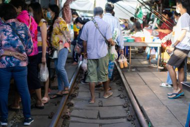 Samut Sakhon, Tayland-15 Kasım 2020: Yüzü maskeli insanlar seyahat ediyor, Mae Klong Demiryolu Pazarı 'ndan taze yiyecek alıyor (Hoop Rom Market) Samut Songkhram Eyaleti' nde yerel bir pazardır..