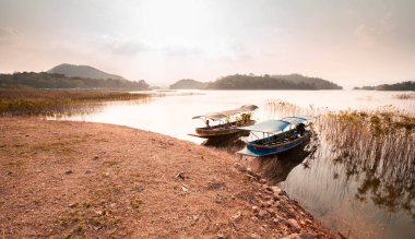 Tayland geleneksel uzun kuyruklu teknesi ve güzel nehir, gökyüzü, dağlar.