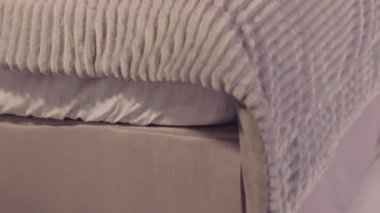 Rahat kıyafetler giymiş güzel bir Meksikalı kız cep telefonunu yavaş çekimde yatağında kontrol ediyor.