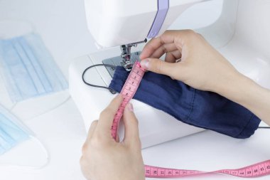 Dikiş işleminin görüntüsünü kapat. Erkek eller dikiş makinesine koruyucu maskeyi dikiyor..