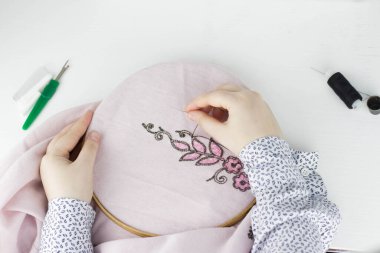 Nakış işleme süreci. Müslüman kadın pembe kumaşa çiçek işliyor.