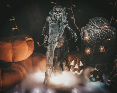 Cadılar Bayramı türünde bir fotoğrafın kompozisyonu. Yükselen ölüm, balkabakları, duman, mezar taşı