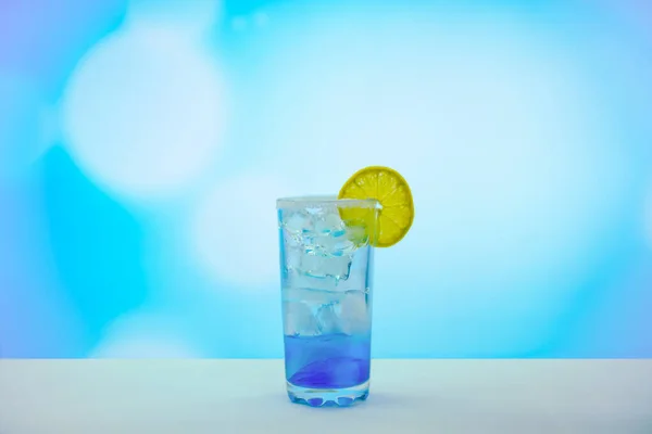 Blue cocktail with ice and lemons in a glass