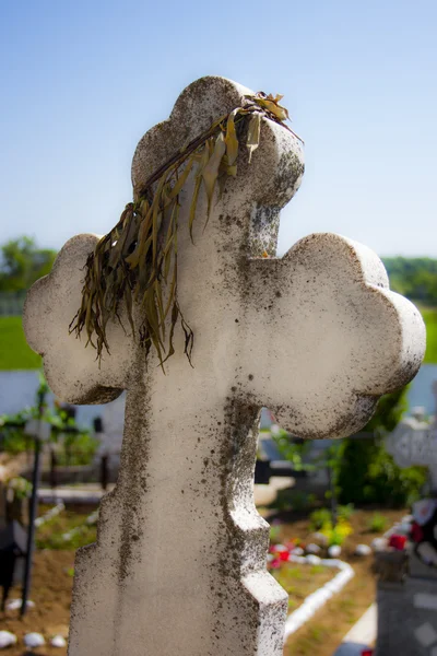 Couronne sèche sur une croix de pierre blanche dans un cimetière — Photo