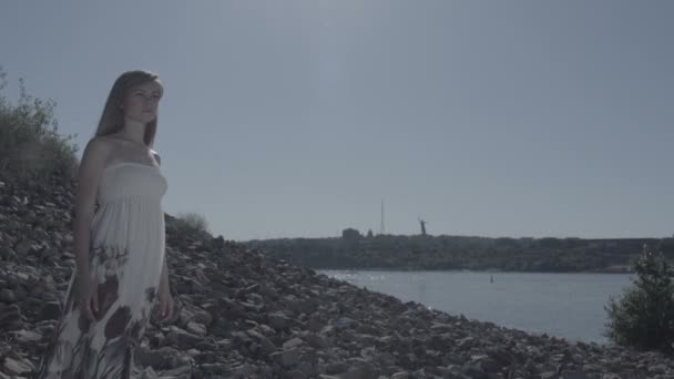 Žena stojí na pobřeží za městem plochý — Stock video