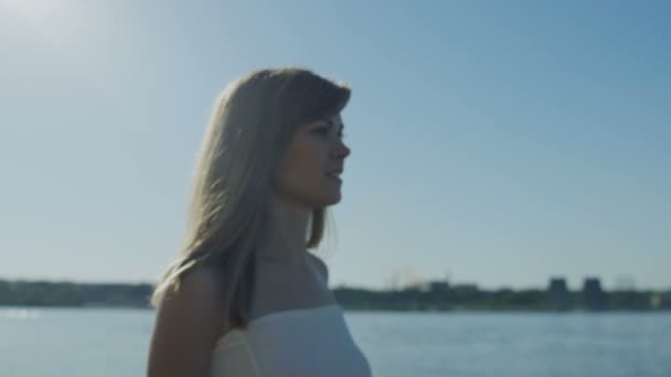 Mujer caminando en la costa detrás de la ciudad verano — Vídeos de Stock