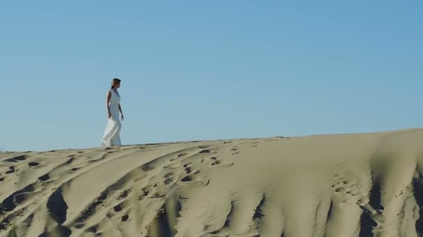 Beyaz elbiseli kadın kumul üzerinde yürüyor — Stok video