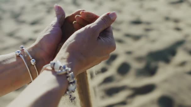 Areia derrama pelas mãos de mulheres na praia — Vídeo de Stock