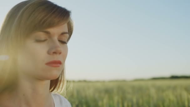 Mulher medita ao ar livre, enquanto os olhos fechados — Vídeo de Stock