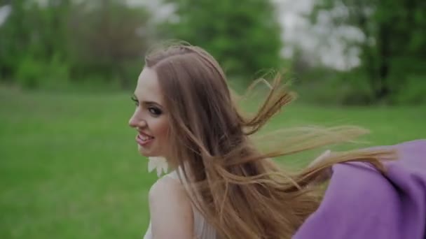 Glückliche Frau mit Umhang läuft durch den grünen Park — Stockvideo