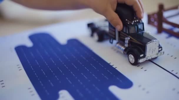 Handen van kind spelen met speelgoed vrachtwagen op tafel — Stockvideo