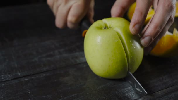 Koch schneidet Apfel auf dunklem Holz in zwei Stücke — Stockvideo