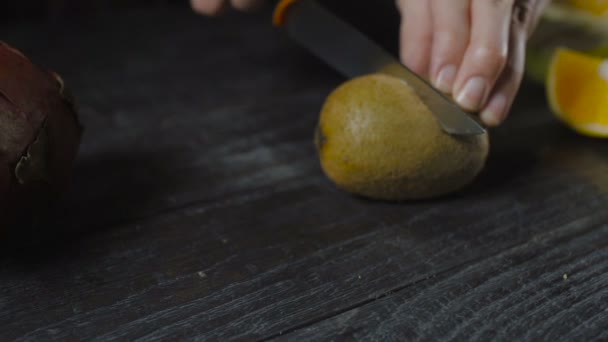 Szef kuchni Kiwi kawałki z nożem na ciemny drewniany stół — Wideo stockowe