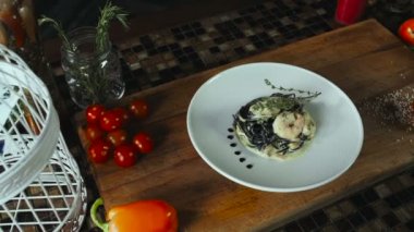 Siyah spagetti karides ve beyaz plaka üzerinde deniz ürünleri ile