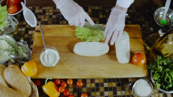 Chef pone hojas de ensalada en un sándwich — Vídeos de Stock