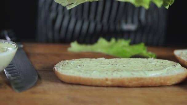 Kocken droppe sallad blad på en smörgås — Stockvideo