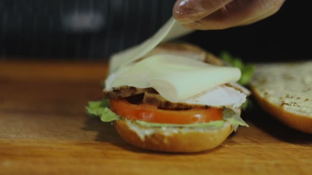 Chef fügt Käsescheiben auf einem Sandwich hinzu
