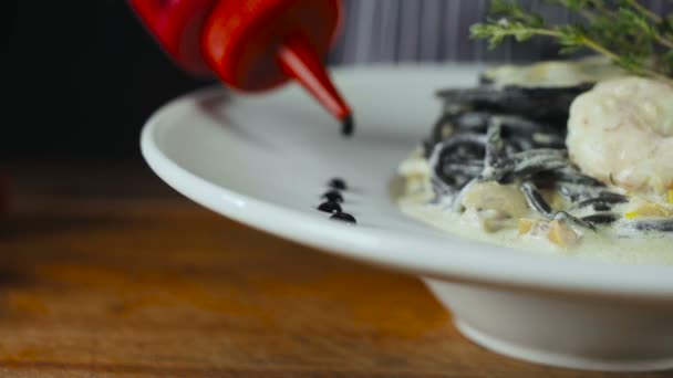 Μαύρο σεφ προσθέτει σάλτσα σε ένα πιάτο — Αρχείο Βίντεο