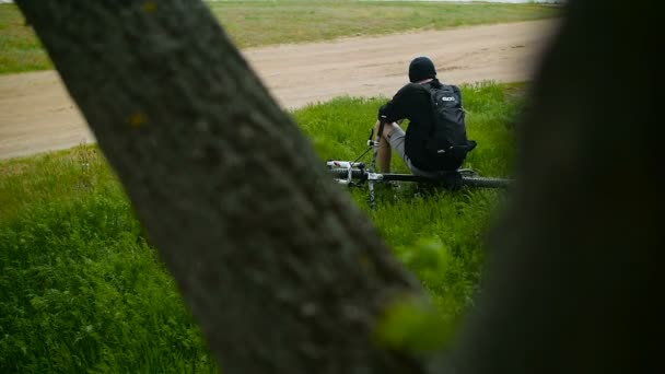 El tipo está descansando en el bosque con una bicicleta — Vídeos de Stock