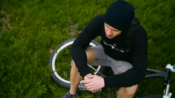 Der Typ ruht sich mit dem Fahrrad im Gras aus — Stockvideo