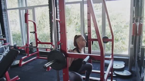 Mulher muscular faz agachamentos com barra na máquina de ferreiro no ginásio — Vídeo de Stock