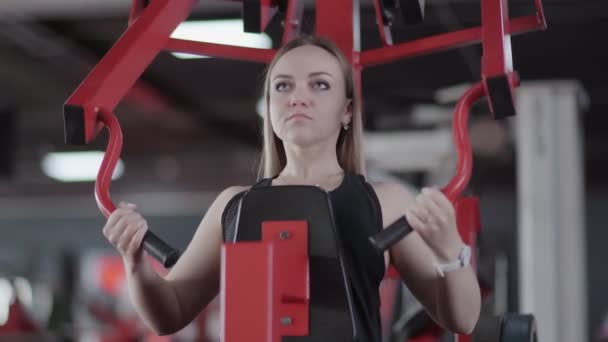 Detailní záběr blondýny žena dělá cvičení na silové trenér stroj v tělocvičně — Stock video