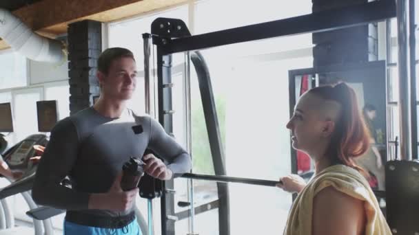 Muskulös kvinna och hennes tränare talar i gymmet — Stockvideo