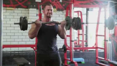 Çekici bir vücut geliştirici halter bisepsi yapıyor.