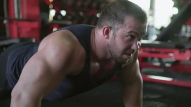 Çekici bir vücut geliştirici spor salonunda şınav çekiyor.