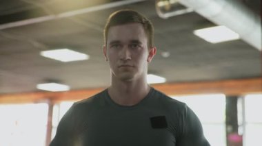 Yaklaş yakışıklı atletik adam spor salonunda halterlerle yan kaldırma egzersizi yapıyor.