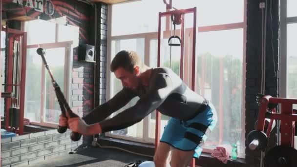 Hombre atlético guapo entrena tríceps y de vuelta en la máquina en el gimnasio — Vídeo de stock