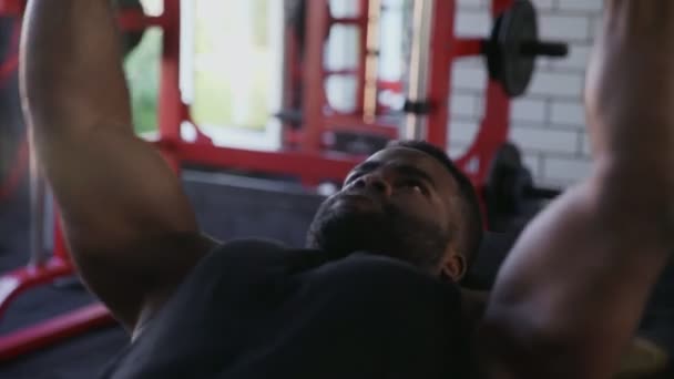 Primo piano dell'uomo afro-americano bodybuilder che esegue la pressa da banco con i manubri in palestra — Video Stock