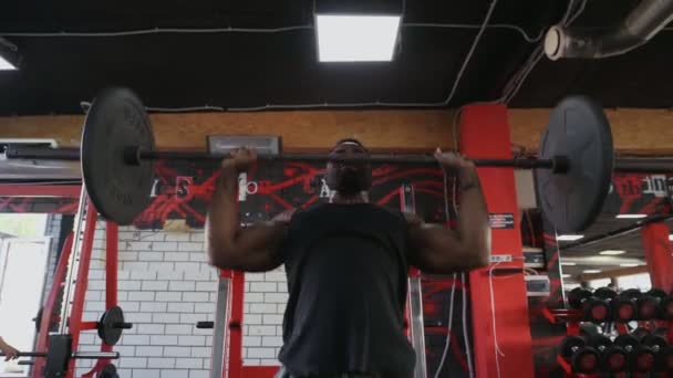 Africano homem americano fisiculturista levanta imprensa barbell no ginásio — Vídeo de Stock