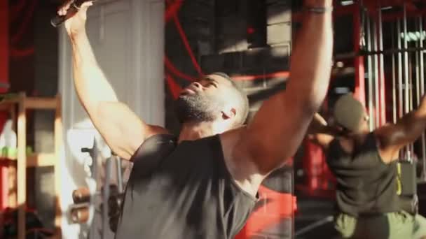 Uomo afroamericano bodybuilder con cuffie wireless che eseguono il pulldown Lat in palestra — Video Stock
