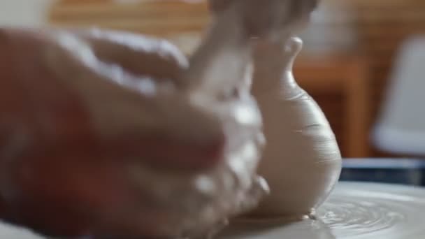 Крупный план человека, формирующего глиняную вазу на вращающемся колесе во время работы в керамике — стоковое видео