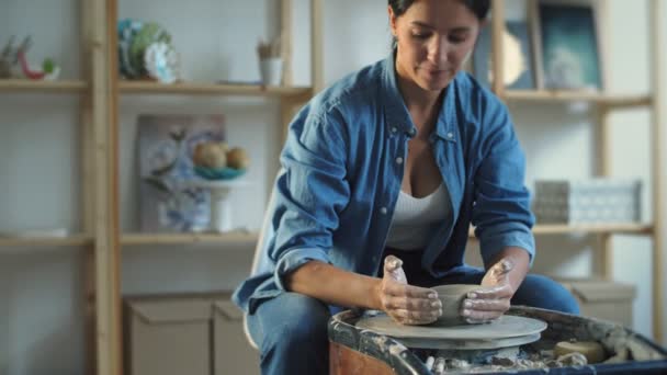 Ceramista femminile che fa pentola di ceramica sulla ruota di ceramica attorcigliata. — Video Stock