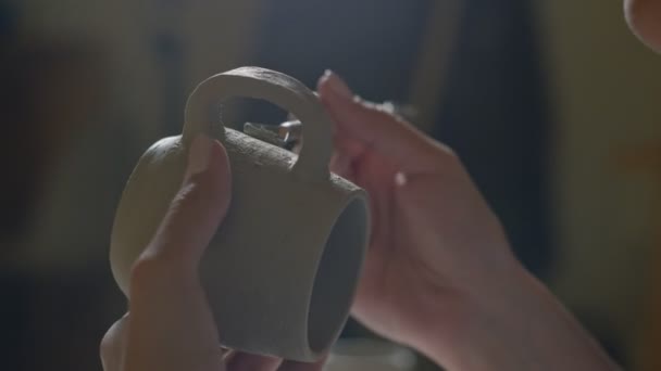 Primo piano di vasaio femminile utilizzando strumento di finitura per fare tazza di argilla ceramica in studio vasaio — Video Stock