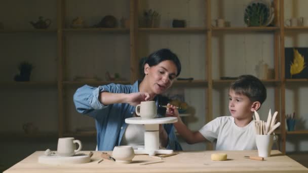 Profesora joven enseña a niño a hacer taza de cerámica — Vídeos de Stock