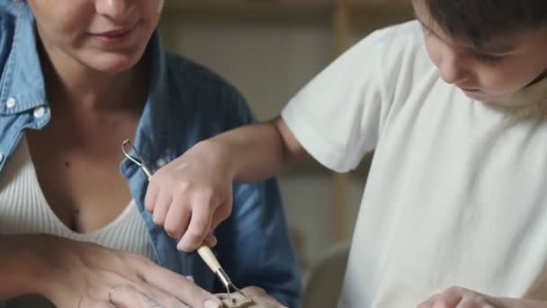 Guru perempuan muda mengajari anak laki-laki bagaimana membuat cangkir keramik — Stok Video